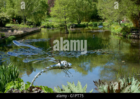 Libelle-Skulptur mit Blick auf einen Teich in Sir Harold hügeliger Gärten in Romsey England uk Stockfoto