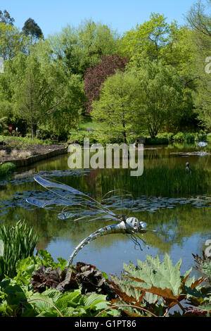 Libelle-Skulptur mit Blick auf einen Teich in Sir Harold hügeliger Gärten in Romsey England uk Stockfoto