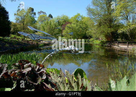 Libelle-Skulptur mit Blick auf einen Teich in Sir Harold hügeliger Gärten in Romsey England uk Stockfoto