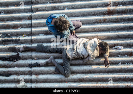 Ein Bild, am Morgen, nach unten auf zwei obdachlose Kinder schlafen auf einem Dach in der Nähe eines Bahnhofs in Janwar, Indien. Stockfoto