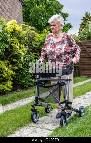 Ältere Frau mit Rollator / Rädern Walker zu Fuß auf der Auffahrt zu Hause üben Stockfoto