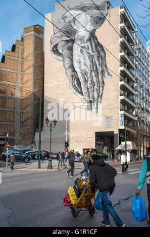 Eine Straße Kunst Wandbild in Form von riesigen zwei Betende Hände drohend über Pireos Straße im Viertel Omonia von Athen, Griechenland Stockfoto