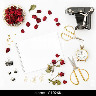 Flache Lay mit Foto Album, rote Rosenblüten, Vintage-Kamera, Schere auf weißem Hintergrund. Mock-up Skizzenbuch Blumen Stockfoto