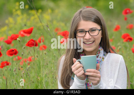 Teen Mädchen trinken Tasse Tee am Mohnfeld Stockfoto