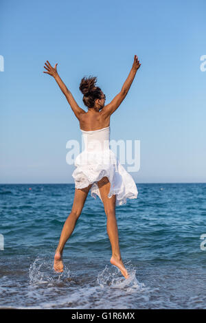 Glückliche Frau am Meer springen. Stockfoto