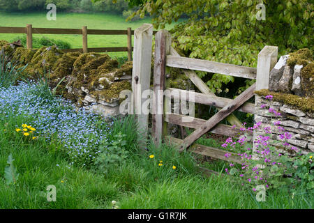 Altes Holztor und Trockenmauer in den Cotswolds. Swinbrook, Oxfordshire, England Stockfoto