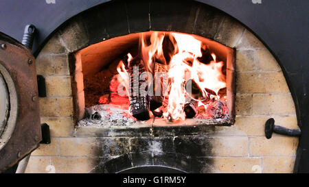 Feuer brennt innen Holz erwärmt Steinofen Stockfoto