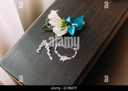 Close-up der Braut Halskette und Ohrringe zusammen mit niedlichen Boutonniere auf rustikalen hölzernen Hintergrund Stockfoto