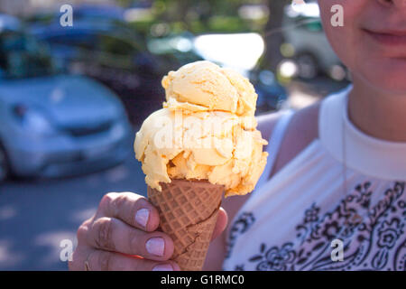 Eine Frau mit gelbe Mango-Melone Eis in der hand Stockfoto