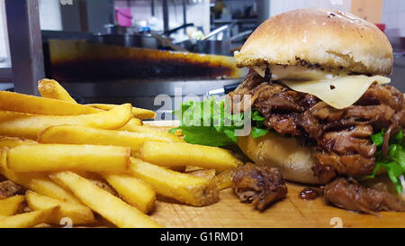 Hausgemachter gezogener Schweinefleisch Burger Mahlzeit, mit Pommes frites in einer Restaurantküche Stockfoto