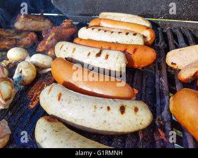 Gegrillte Bratwurst und Würstchen auf einen Gas-Grill, zwischen Pilzen und Rippen Stockfoto