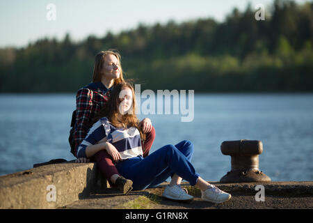 Zwei Freunde Teen Mädchen verbringen Zeit zusammen an der Pier des Flusses. Stockfoto