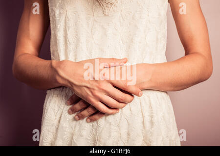 Eine junge Frau trägt ein weißes Kleid hat Bauchschmerzen Stockfoto