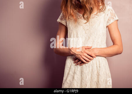 Eine junge Frau trägt ein weißes Kleid hat Bauchschmerzen Stockfoto