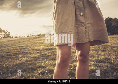 Eine junge Frau den Rock weht im Wind, wie sie bei Sonnenuntergang in einem Park steht Stockfoto