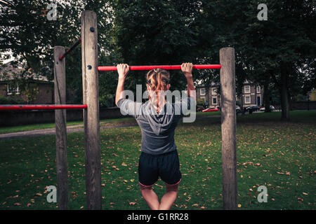 Eine junge Frau tut Pullups im park Stockfoto