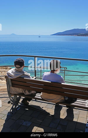 Touristen sitzen auf Bank Blick auf Kvarner Bucht, Rabac, Istrien, Kroatien. Stockfoto