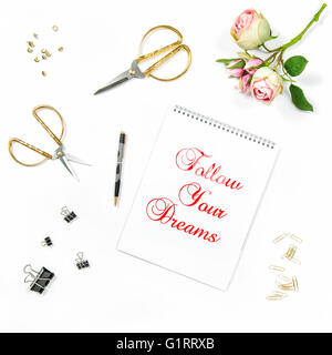 Flache Laien stieg mit Skizzenbuch, Blumen, goldenen Accessoires auf weißem Hintergrund. Motivation Zitat folgen Your Dreams Stockfoto