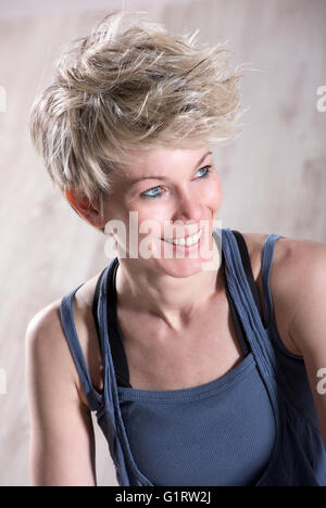 Porträt der einzelnen sportlichen schöne blonde Frau lächelnd und Blick seitwärts über Stein Marmor Hintergrund Stockfoto