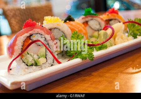 Ein Regenbogen-Sushi-Rolle auf einem Tisch mit unscharfen Hintergrund. Stockfoto