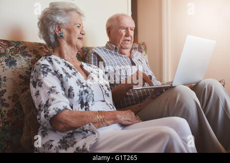 Innenaufnahme des senior paar sitzt auf einer Couch mit einem Laptopcomputer. Alter Mann und Frau auf einem Sofa mit Laptop. Stockfoto