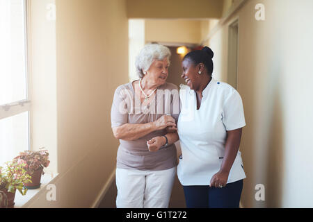 Porträt von glücklich weibliche Bezugsperson und senior Woman walking zusammen zu Hause. Professionelle Betreuer kümmert sich um ältere Menschen woma Stockfoto