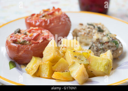 gehackte Kartoffeln mit Zwiebeln Grateed und gefüllte Champignons und Tomaten Stockfoto