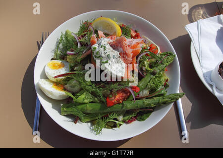 Frischer Salat mit Lachs, Ei und grüner Spargel auf einem weißen Teller. Stockfoto