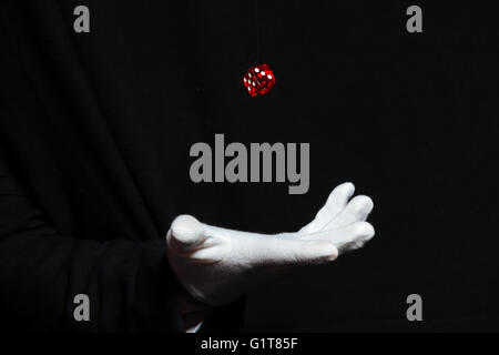 Hand des Magiers Mann in weißen Handschuhen zeigt Tricks mit Würfeln über schwarzem Hintergrund in der Luft fliegen Stockfoto