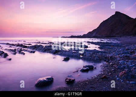 Das felsige Ufer an Spekes Mühle Mündung an der Küste von North Devon in der Abenddämmerung in der Nähe von Hartland, England. Stockfoto