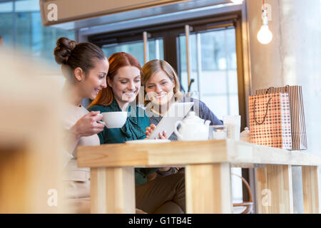 Lächelnde Frauen Tee trinken und den Austausch von digital-Tablette am Café-Schalter Stockfoto