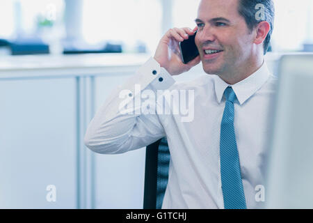 Lächelnde Geschäftsmann reden über Handy im Büro Stockfoto