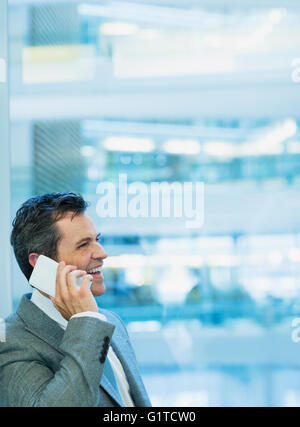 Lächelnde Geschäftsmann reden über Handy im Büro Stockfoto