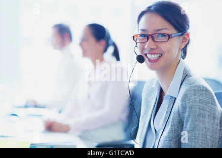 Porträt von lächelnden Geschäftsfrau im Gespräch am Telefon mit Kopfhörer Stockfoto