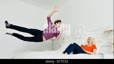 Frau ansehen verspielt Mann springt auf Bett Stockfoto