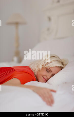 Gelassene Frau schläft auf Bett Stockfoto