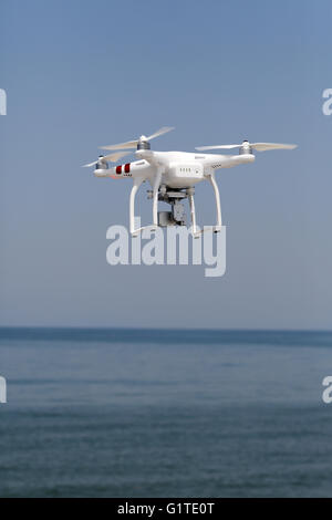 Weiße Drohne Quad Copter mit in den klaren blauen Himmel fliegen Stockfoto