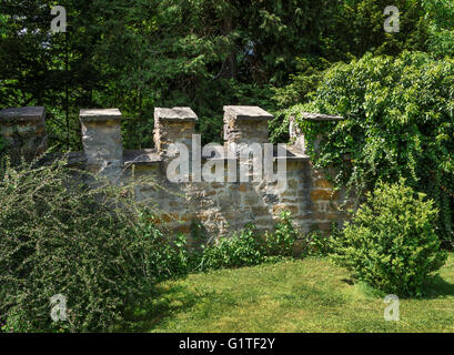 Burgmauer mit Zinnen in einem Garten Stockfoto