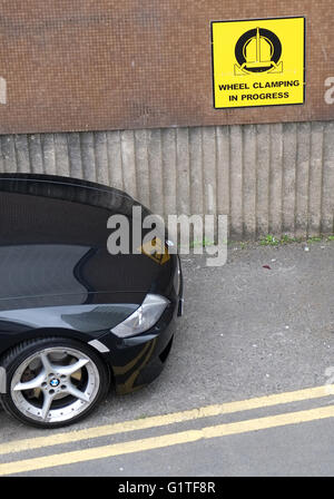 Illegales parken, schwarzen Auto parkte auf doppelte gelbe Linien neben ein Warnhinweis über Rad spannen. 24. Mai 2016 Stockfoto