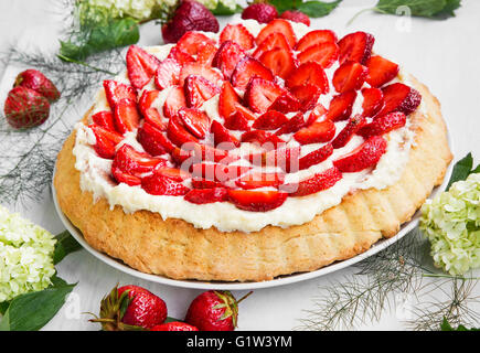 Erdbeer-Früchte-Tarte mit Vanille-Sahne, Erdbeeren und weißer Blumen Dekoration Stockfoto