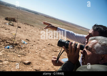 Kurdische Flüchtlinge sehen die alliierten Luftangriffe auf die syrische Stadt Kobani, von einem Hügel, die mit Blick auf die Stadt, in der Nähe der türkischen Stadt Suruc an der türkisch-syrischen Grenze. Tausende von Kurden wurden gezwungen, die syrische Stadt Kobani aufzugeben, die von islamischen Staat Truppen belagert wird. Die meisten von ihnen Leben in Flüchtlingslagern in der türkischen Stadt Suruc. Stockfoto