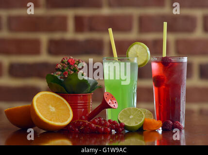 Gläser für Saft, Obst und Blumen auf einem Tisch Stockfoto