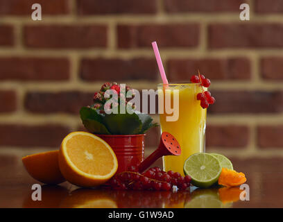 Gläser für Saft, Obst und Blumen auf einem Tisch Stockfoto