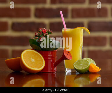 Gläser für Saft, Obst und Blumen auf einem Tisch Stockfoto