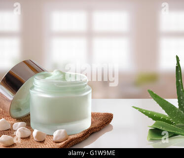 Offenen Glas mit Gesichts- oder Creme Aloe Vera auf Sackleinen. Mit Deckel, kleinen Steinen und Aloe-Pflanze. Windows-Hintergrund. Stockfoto