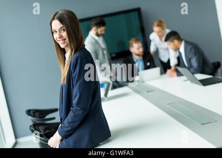 Geschäftsfrau im Büro mit ihren Kollegen hinter ihr Stockfoto