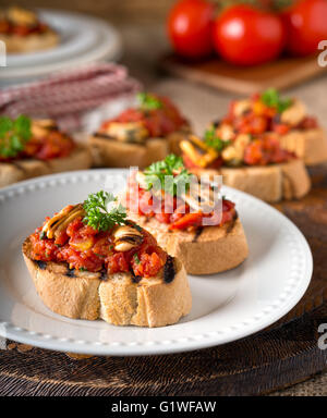 Leckere Muscheln Bruschetta mit Tomaten, Petersilie, Olivenöl und Knoblauch auf gegrilltes Baguette. Stockfoto