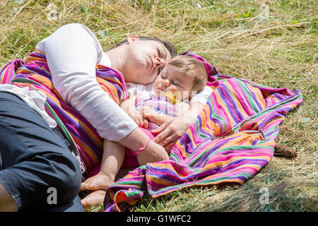 Mutter und schönen einjährigen Baby schlafen auf bunte Decke in der Sonne Stockfoto