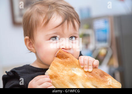 Nahaufnahme des schönen einjährigen Baby beißt eine großes Stück Brot Stockfoto