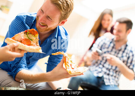 Mann isst Pizza mit Freunden zu Hause Stockfoto